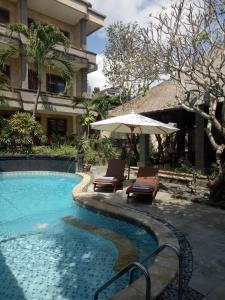 a swimming pool with two chairs and an umbrella at Ellies Hotel in Nusa Dua