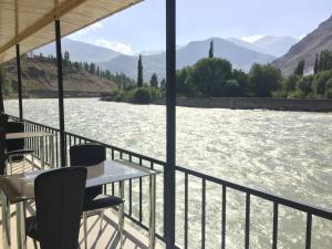 a table and chairs on a balcony next to a river at Zarya Hotel in Khorog