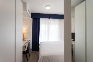 a bedroom with a bed and a desk and a window at Fantinello Hotel in Caorle