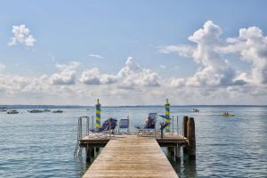 a dock with two chairs and a table on the water at MaisonMe Boutique Hotel in Bardolino