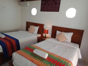 a bedroom with two beds and a pillow on the bed at The Umah Prahu in Nusa Penida