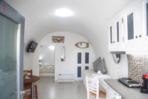 a kitchen and living room with white walls and a table at White Side Suites in Oia