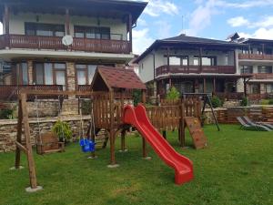um parque infantil em frente a uma casa com escorrega em Къщи за гости БАШЕВИ em Sarnitsa