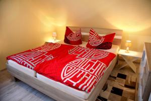 1 cama con almohadas y manta roja y blanca en Ferienwohnung „Kranich“ en Mirow