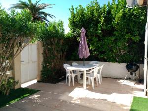ヴィック・ラ・ガルディオルにあるPetit Loft T2 bis mezzanine avec jardin et piscineのパティオ(パラソル付きのテーブルと椅子付)