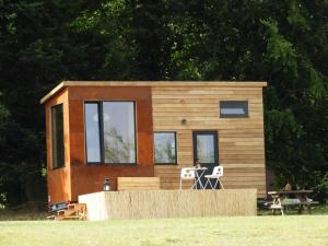 uma pequena casa sentada em cima de um campo em La Tiny du Parc : Saint Symphorien des Monts em Saint-Symphorien-des-Monts