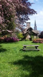 Saint-Symphorien-des-Monts的住宿－La Tiny du Parc : Saint Symphorien des Monts，坐在建筑物前面的草上的一个长凳