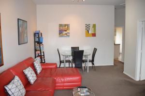 a living room with a red couch and a table at Akaroa Central Apartment in Akaroa