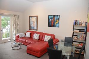 a living room with a red couch and a glass table at Akaroa Central Apartment in Akaroa