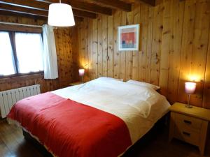 a bedroom with a bed with a red and white blanket at Chalet Des Sangliers in Séez
