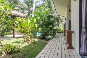 una pasarela de madera que conduce a una casa con palmeras en Baan Manaao, en Hinkong