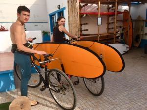 a man is holding a surfboard on a bike at Ethic Surf House in Ferrel +66 photos