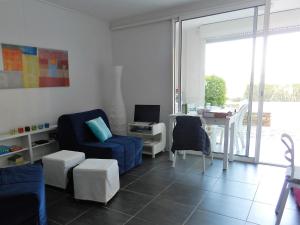 a living room with a blue chair and a table at Appartement les Pieds dans l'eau ! in Le Lavandou