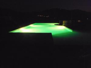 una piscina illuminata di notte con luci verdi di Aecolibrium Country House a Pastena