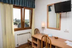 a room with a desk and a tv and a window at Hotel Las Anclas in El Astillero