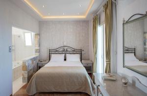 a bedroom with a bed and a tub and a mirror at Contaratos Beach Hotel in Naousa