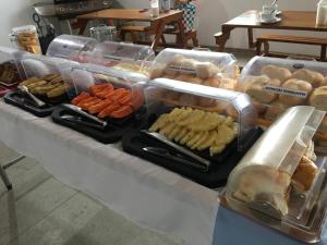 un buffet avec de nombreux types de denrées alimentaires dans des récipients en plastique dans l'établissement Maraga Beach Hostel, à Maragogi