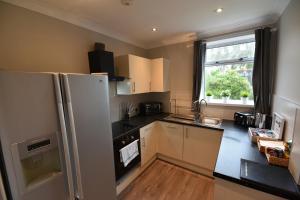 a small kitchen with a refrigerator and a window at Sighthill 3 Bedrooms with Private Garden in Edinburgh +7 photos