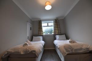 - 2 lits dans une petite chambre avec fenêtre dans l'établissement Sighthill 3 Bedrooms with Private Garden, à Édimbourg