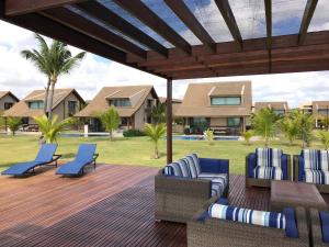 un patio con sillas y una terraza con palmeras. en Charmoso Flat Nui Supreme - Térreo, en Porto de Galinhas