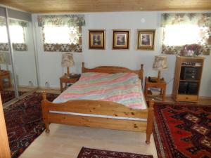 um quarto com uma cama de madeira e 2 janelas em Semestervilla vid sjö em Arkelstorp