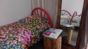 a bed with a colorful comforter and a mirror at A Casa da Avó... in São Vicente