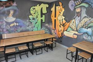 a room with benches and a wall with a mural at FULL HOUSE capsule hostel in Rivne