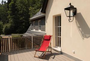 a red chair sitting on a porch next to a window at Ferienheim Kuckuckswinkel - Familiensuite Marlene in Schöna