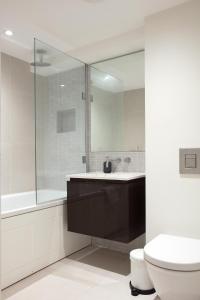 W łazience znajduje się umywalka, toaleta i lustro. w obiekcie Hampden Apartments - The George w mieście Windsor