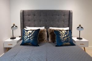 a bedroom with a bed with blue pillows and two lamps at Hampden Apartments - The George in Windsor