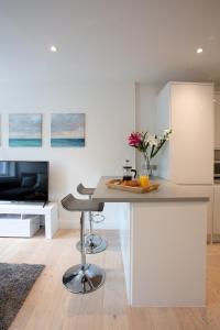 a white kitchen with a table and a tv at Hampden Apartments - The George in Windsor