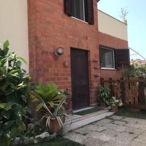 uma casa de tijolos com uma porta preta e um alpendre em Mirella's House ViaVerona em Ardea