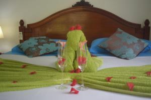 une personne en costume vert debout sur un lit avec des verres à vin dans l'établissement Chalet Bamboo Vert, à La Digue