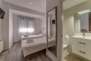 a bathroom with two beds and a mirror at Hostal Lar in Burgos