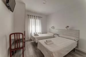 a bedroom with two beds and a chair at Hostal Lar in Burgos