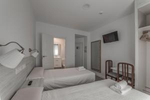 a white bedroom with two beds and a mirror at Hostal Lar in Burgos