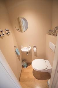 een badkamer met een toilet, een wastafel en een spiegel bij Melrose in De Haan