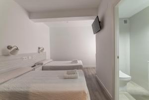 a white room with two beds and a toilet at Hostal Lar in Burgos