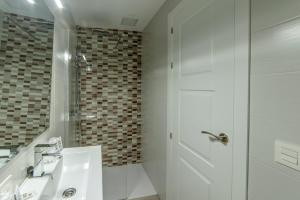 a white bathroom with a shower and a sink at Hostal Lar in Burgos