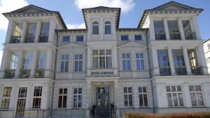 a large white building with blue windows at Hotel Fortuna in Heringsdorf