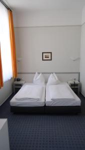 1 dormitorio con 2 camas blancas y ventana en Hotel Fortuna, en Heringsdorf