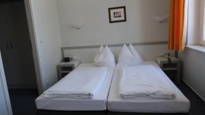 a bedroom with two beds with white sheets and pillows at Hotel Fortuna in Heringsdorf