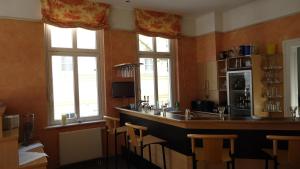 a kitchen with a bar with chairs and windows at Hotel Fortuna in Heringsdorf +22 photos