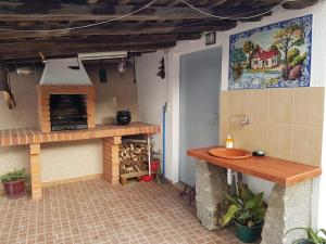 an outdoor kitchen with a sink and a fireplace at Casa do Neto Tiago in Fundão