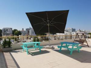 two picnic tables and an umbrella on a roof at NEX Hostel in Nicosia