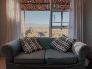 a couch with two pillows sitting in front of a window at Die Lemoenhuis in Calvinia