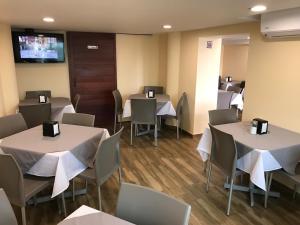 a dining room with tables and chairs and a tv at Hotel Oriente in Veracruz