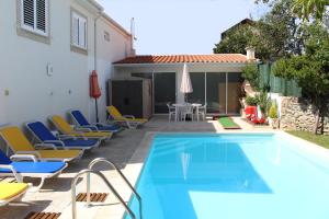 a pool with chairs and a table and a house at Casa de Vale Benfeito - Turismo Rural in Macedo de Cavaleiros