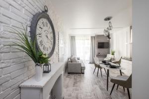 a living room with a large clock on a brick wall at Good Time Apartment Warsaw Vista in Warsaw