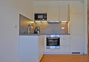 a kitchen with white cabinets and a sink and a stove at Gästehaus Walser in Unterbrunn